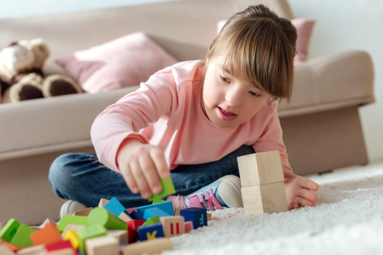 Kid with down syndrome playing with toy cubes